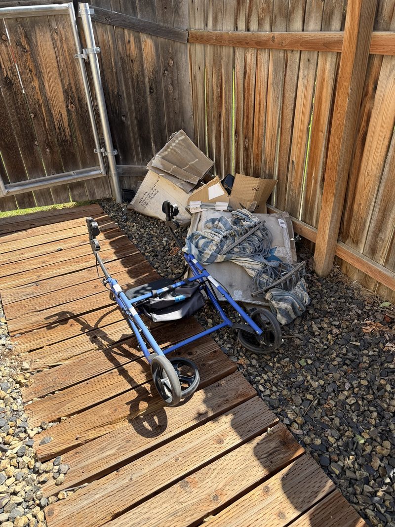 Flattened cardboard, a mattress pad and household odds and ends piled in a side yard corner in Meridian, Idaho