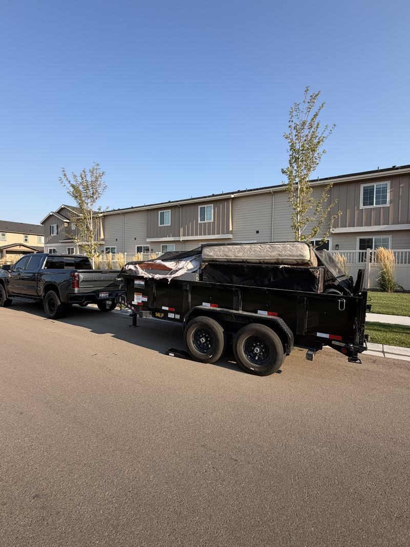 HaulWorks truck and trailer loaded with a mattress and furniture for removal in the Treasure Valley